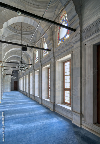 Passage in Nuruosmaniye Mosque  a public Ottoman Baroque style mosque  with columns  arches and floor covered with blue carpet lighted by side windows located in Shemberlitash  Fatih  Istanbul  Turkey