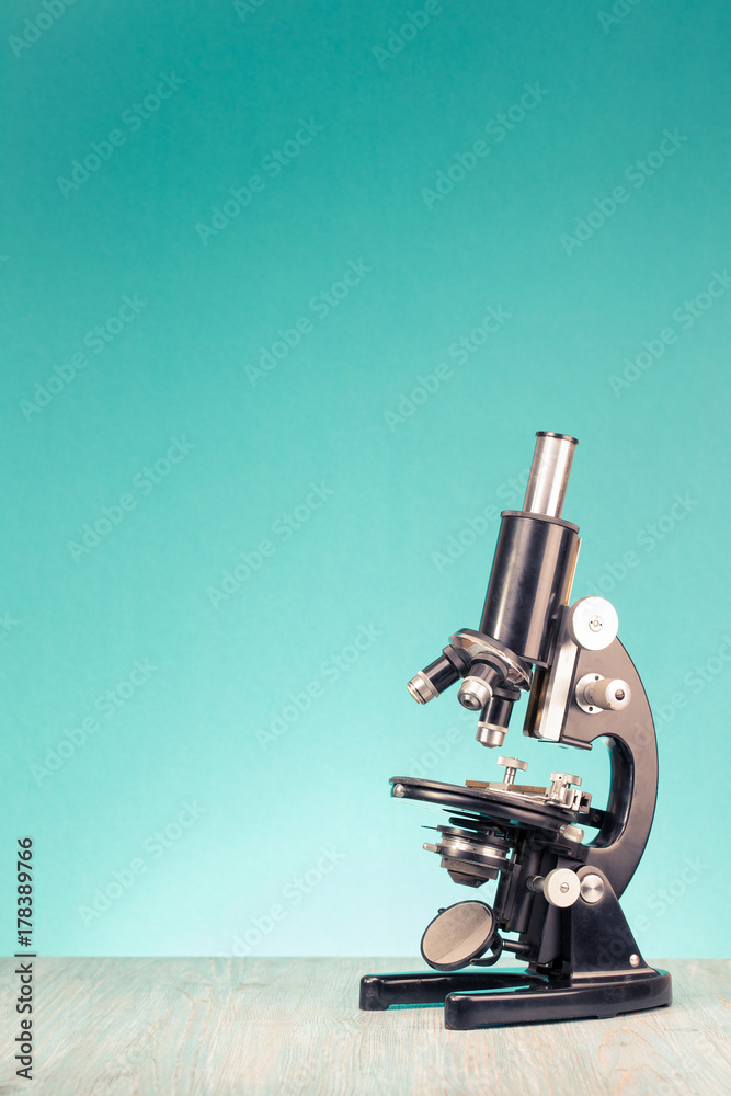 Retro old scientific laboratory microscope circa 1940s on wooden table  front gradient mint green background. Vintage style filtered photo Stock  Photo | Adobe Stock