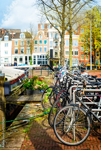 Row of bicycles standing next to canal in Amsterdam at spring, Netherlands, retro toned
