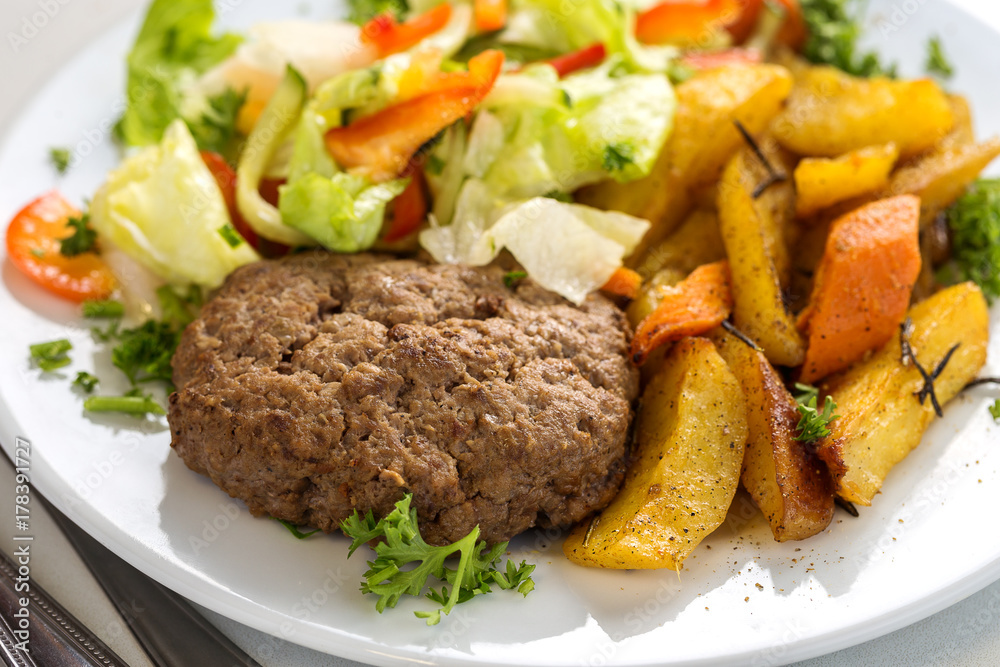 Tasty beef cutlet with salad and potato wedges Tasty beef cutlet with salad and potato wedges