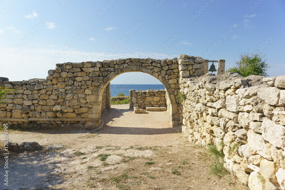 The blue expanse of the black sea is visible through the arch in the ancient wall