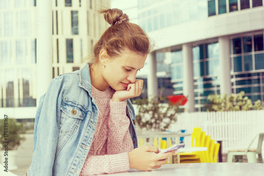 European young woman in casual clothes in a cafe reading a message in a smartphone. toned photo European young woman in casual clothes in a cafe reading a message in a smartphone. toned photo