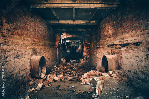 Old dark creepy underground brick tunnel or corridor or sewer pipeline at abandoned ruined industrial factory