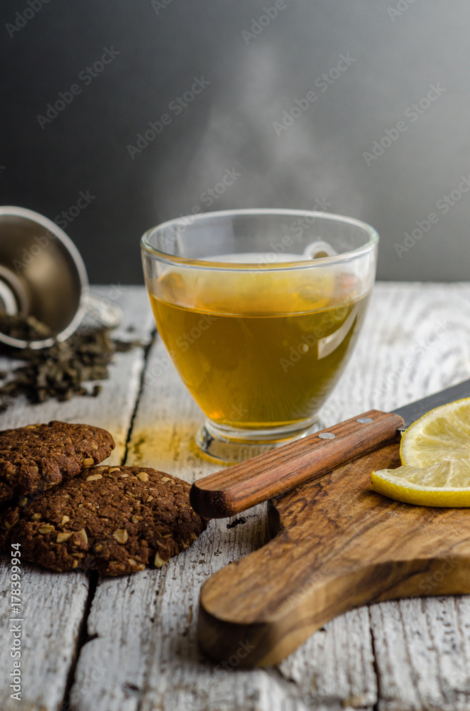 Hot green tea with cookies and lemon slices around Hot green tea with cookies and lemon slices around