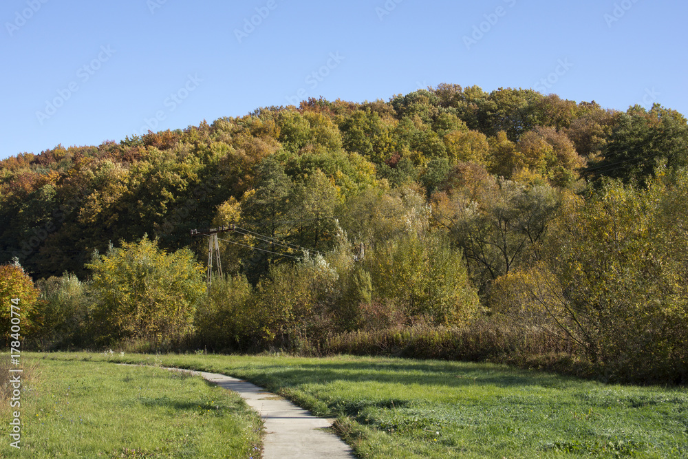 Hills in Hungary with forest in autumn colors with a blue sky and a foot path