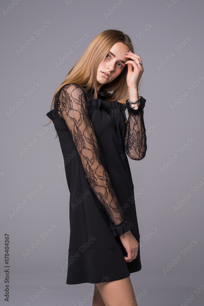 Young brunette lady in black dress posing on grey background Young brunette lady in black dress posing on grey background