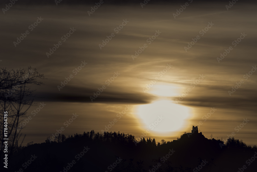 Sunrise with forested mountain silhouette with a castle
