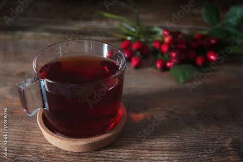Cup of Tea from rosehip tea and bouquet of rose hips on the wooden background.Seasonal, vitamin drink.Cup Of Tea Or Coffee. Dried Fruits.