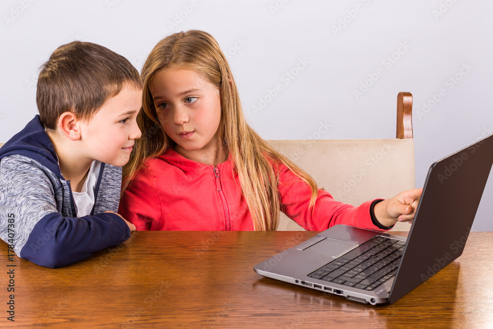 Young girl shows something to her brother on a laptop Young girl shows something to her brother on a laptop