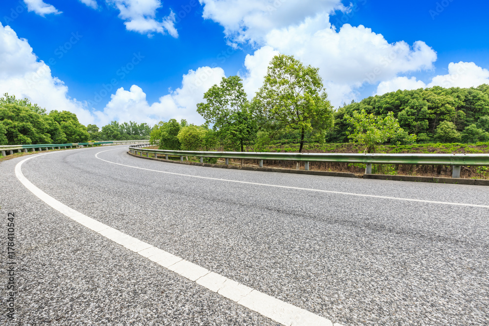 asphalt road and green forest under the blue sky asphalt road and green forest under the blue sky