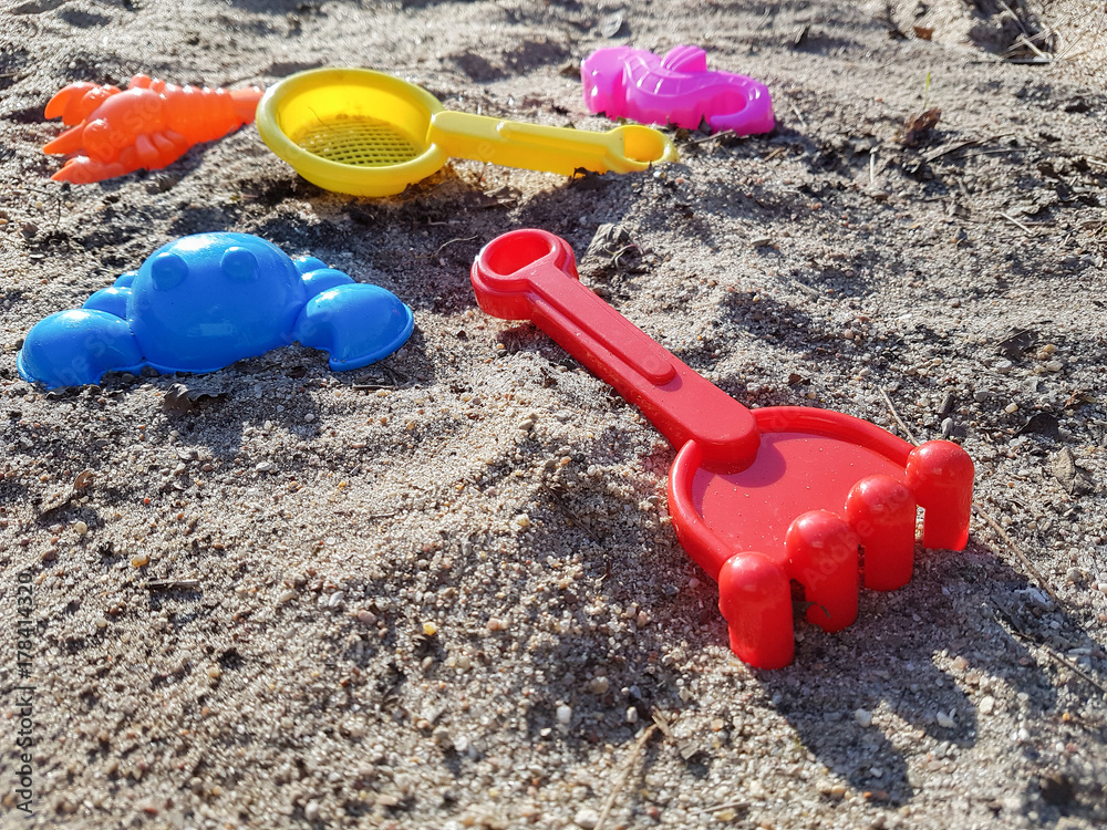 Mehrere bunte Sandformen für Kinder als Spielzeug in Sandkiste bei Sonnenschein Mehrere bunte Sandformen für Kinder als Spielzeug in Sandkiste bei Sonnenschein