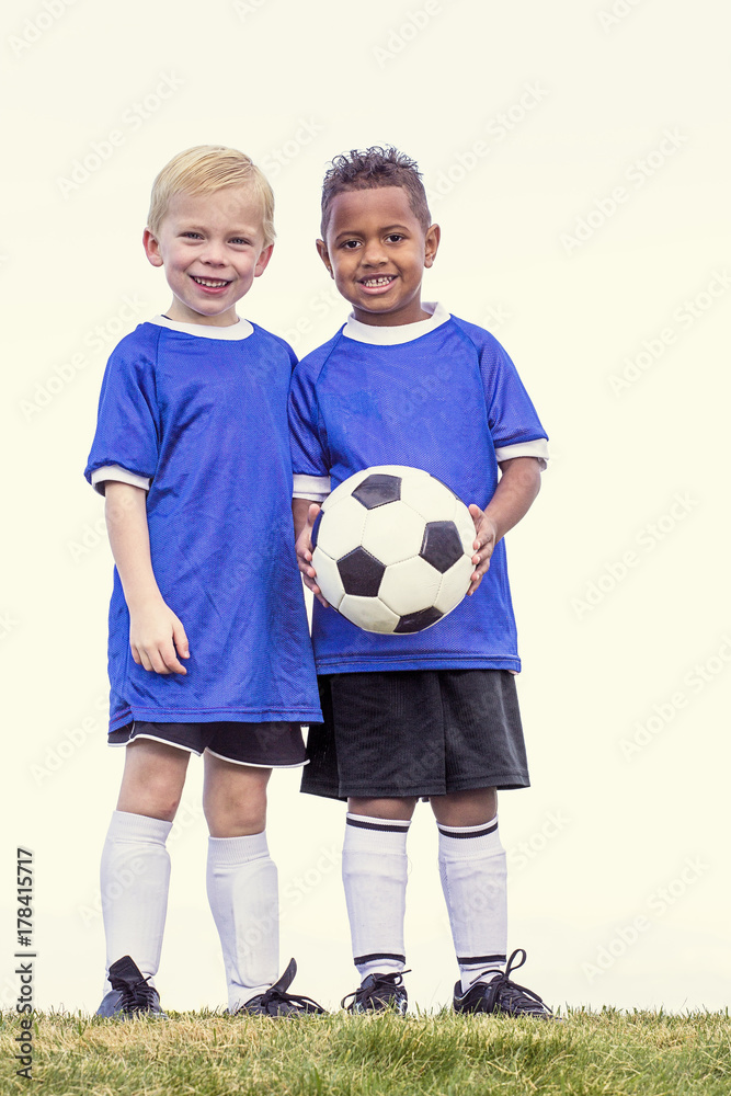 Full length view of two youth recreation league soccer players. Two diverse little boys standing on a grass field Full length view of two youth recreation league soccer players. Two diverse little boys standing on a grass field