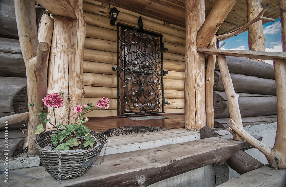 porch with door of wooden rural house with flowers on its steps
