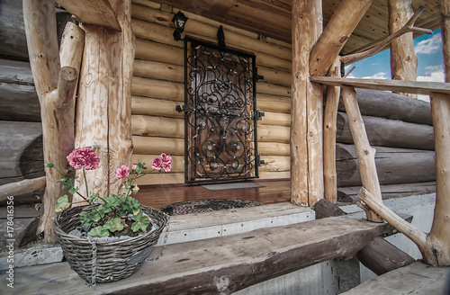 porch with door of wooden rural house with flowers on its steps