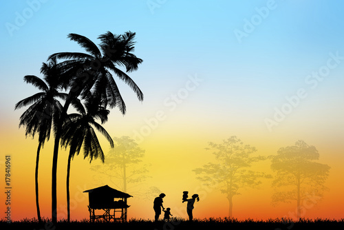 Silhouette of Asian farmers working at rice field on blurry sunset.