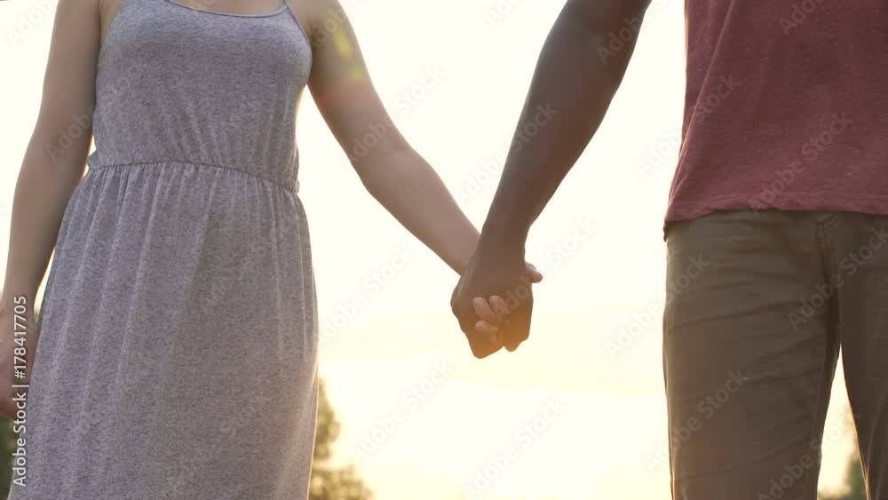 Boyfriend and girlfriend firmly clasp hands on a sunset background, together Boyfriend and girlfriend firmly clasp hands on a sunset background, together