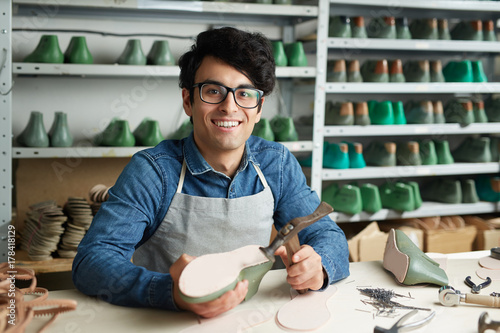 Self-employed shoemaker or repairman looking at camera during work photo