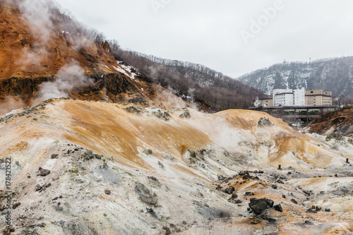 Noboribetsu Jigokudani (Hell Valley) with hotel and mountain: The volcano valley got its name from the sulfuric smell, extremely high heat and steam spouting out of the ground in Hokkaido, Japan. © artitwpd