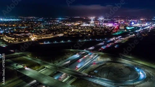 Urban aerial drone time lapse in motion or hyperlapse at night flying towards a highway with cars and traffic showing the on and off ramp circles indicative of the fast paced futuristic city lifestyle