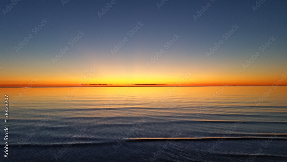 Fototapeta premium beautiful orange sunset on silent sea water