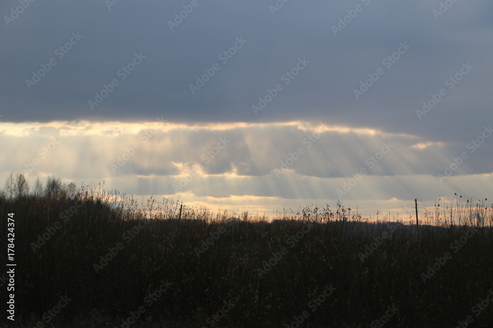 The sky with large clouds and the rays of the sun between them.