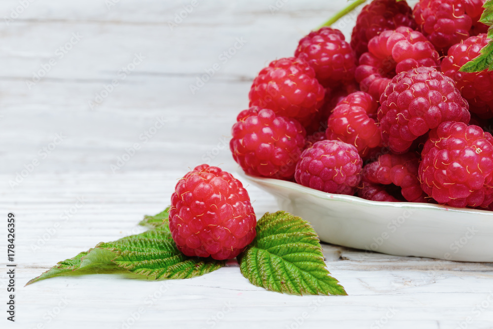 Raspberries in a bowl on a wooden white table Raspberries in a bowl on a wooden white table