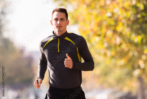 Young man wearing sportswear and running in forest at mountain