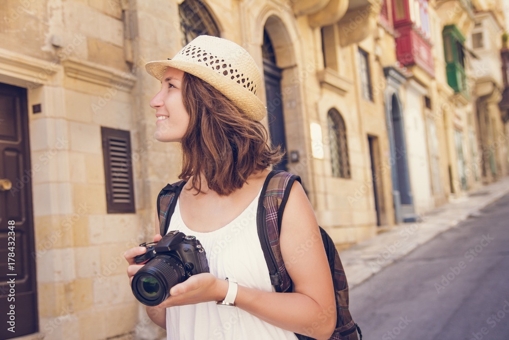 Young woman tourist with camera sightseeing in Valletta, Malta
