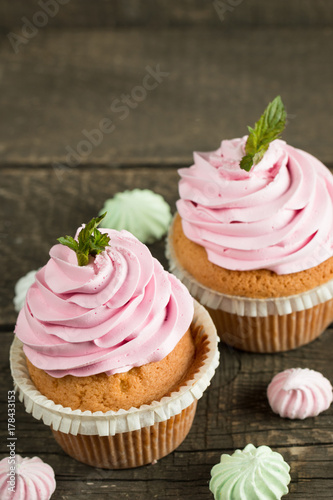 Closeup of cupcakes with vanilla, berries, pink and white cream, chocolate and sprinkles on wooden background. Selective focus. Sweet dessert tasty food concept muffin.