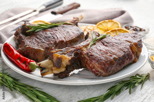 Plate with delicious grilled steaks on wooden table