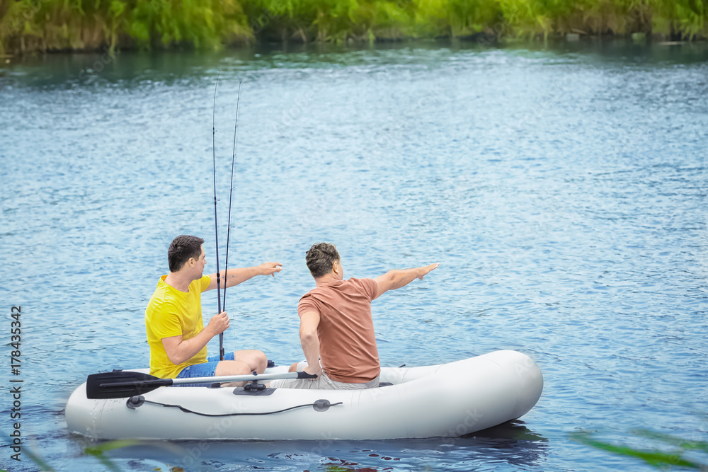 Two men fishing from inflatable boat on river Two men fishing from inflatable boat on river