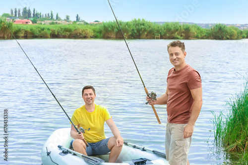 Two men fishing from inflatable boat on river