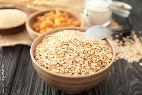 Bowl with oatmeal flakes on wooden background