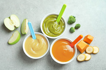Bowls with baby food on grey background