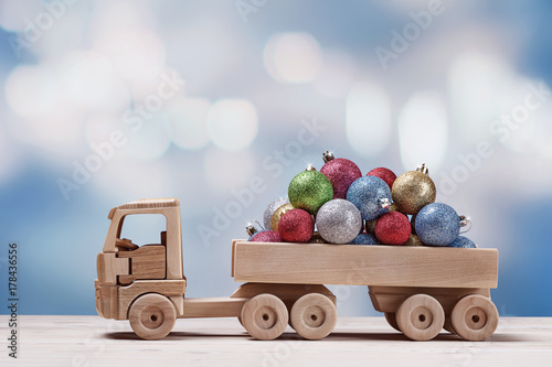 Toy car with christmas balls on festive background.