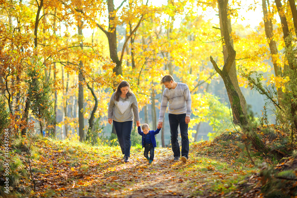happy family walking in beautiful autumn park at sunset.