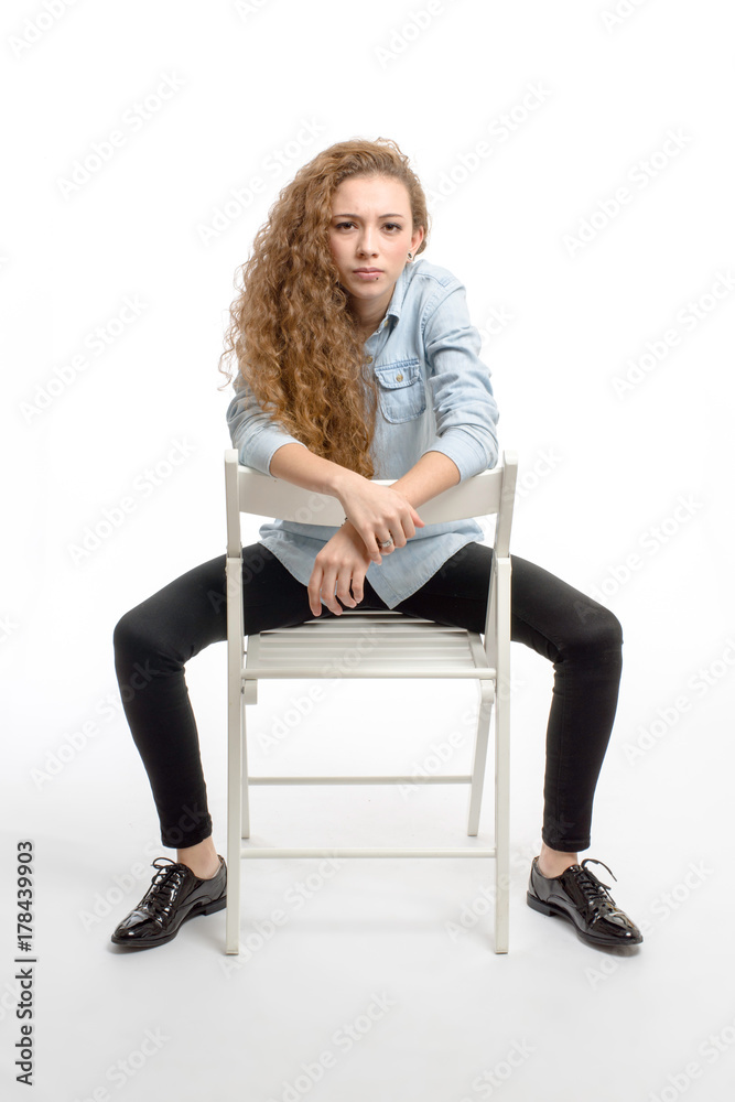 young modern and cheerful girl sitting on chair on white background young modern and cheerful girl sitting on chair on white background