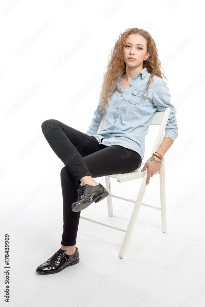 young modern and cheerful girl sitting on chair on white background young modern and cheerful girl sitting on chair on white background