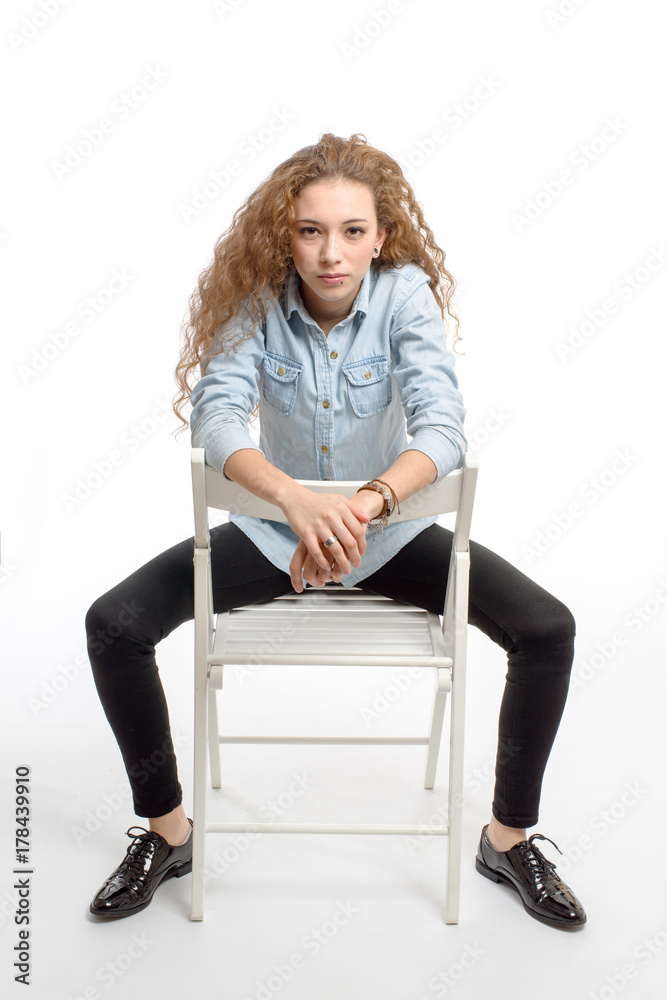 young modern and cheerful girl sitting on chair on white background young modern and cheerful girl sitting on chair on white background