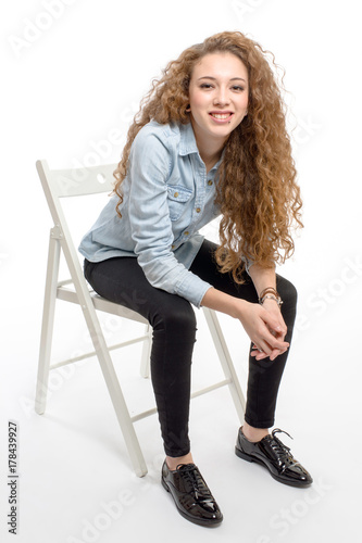 young modern and cheerful girl sitting on chair on white background