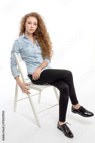 young modern and cheerful girl sitting on chair on white background