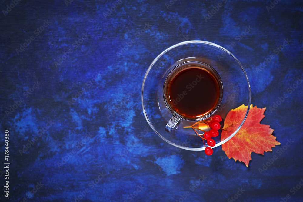 Black coffee in clear dishes on the autumn red leaves on a blue background