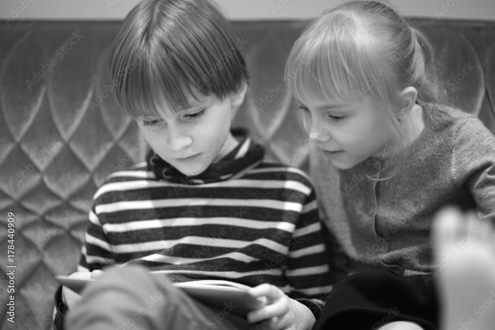 Boy and girl sitting on the couch watching the computer screen Boy and girl sitting on the couch watching the computer screen