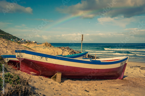 Fishing boats on the beach with a rainbow in the sky at Fish Hoek, South Africa