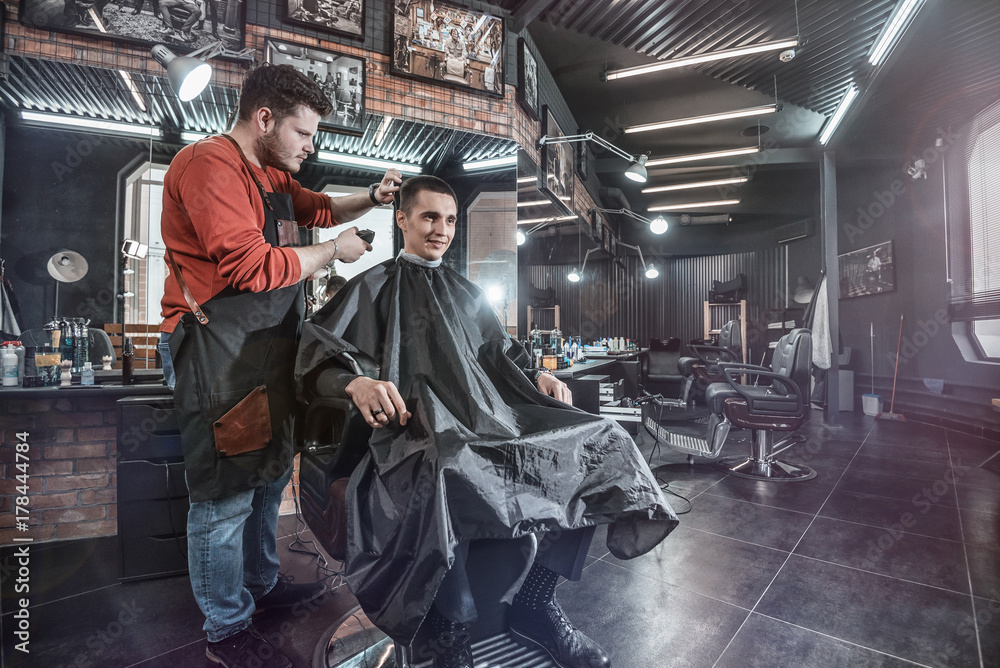 haircut in men room/ Barber cutting in barbershop. Interior of hairdressing salon
