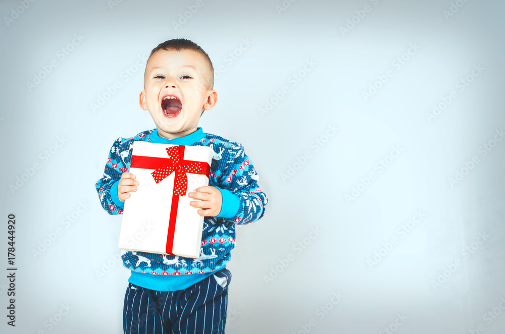 A very emotional child sweater with a reindeer on the eve of the new year holding gift in hand A very emotional child sweater with a reindeer on the eve of the new year holding gift in hand