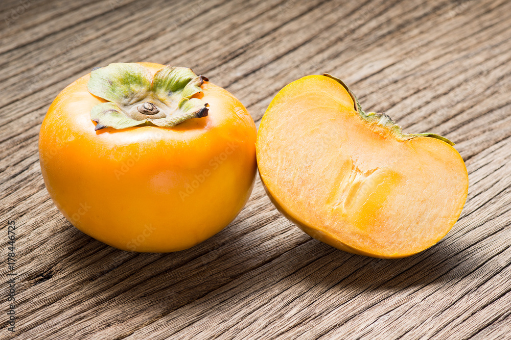 fresh persimmon fruit and section on old wood ( Diospyros virginiana L., EBENACEAE) fresh persimmon fruit and section on old wood ( Diospyros virginiana L., EBENACEAE)