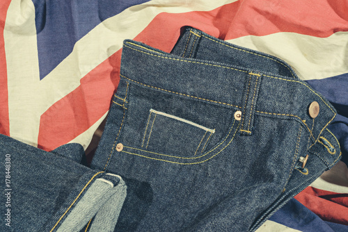 Blue Jeans Denim, 100% Cotton Unsanforized Denim Red Selvage Jeans on The Flag of England vintage tone color style background, selective focus (detailed close-up shot) photo