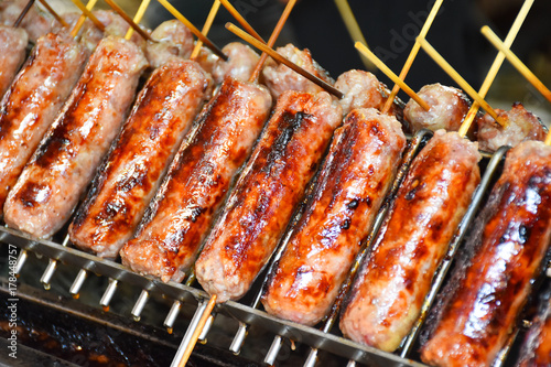 Grilling sausages on barbecue grill with stick for easy eating. BBQ in the garden.