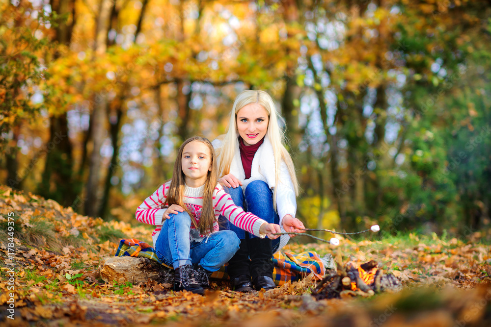 happy family outdoors in a beautiful park, fry marshmallows at the stake. happy family outdoors in a beautiful park, fry marshmallows at the stake.